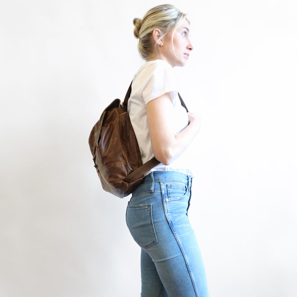Side view of model wearing 1904 maxwell, size medium, as a backpack. 