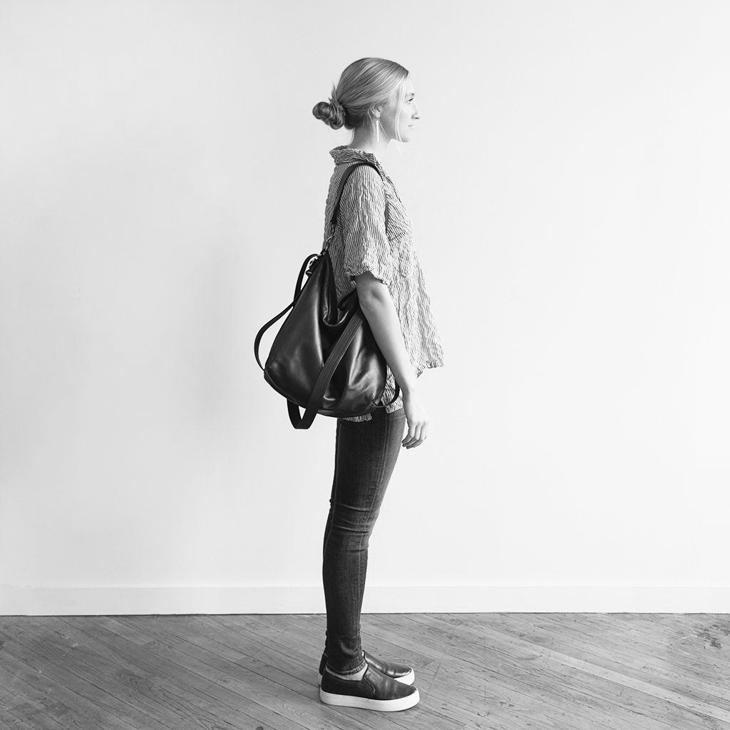 Model holding a hobo pack original on shoulder, in size extra large, for size demonstration. The size of the extra large hobo pack original is approximately the same as the extra large original city safari single zip. 