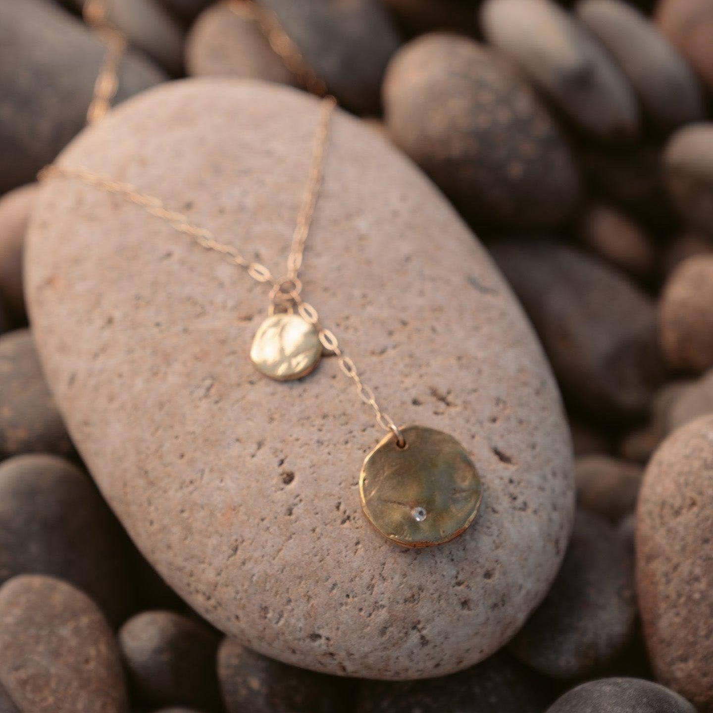 necklace pictured atop a beach stone