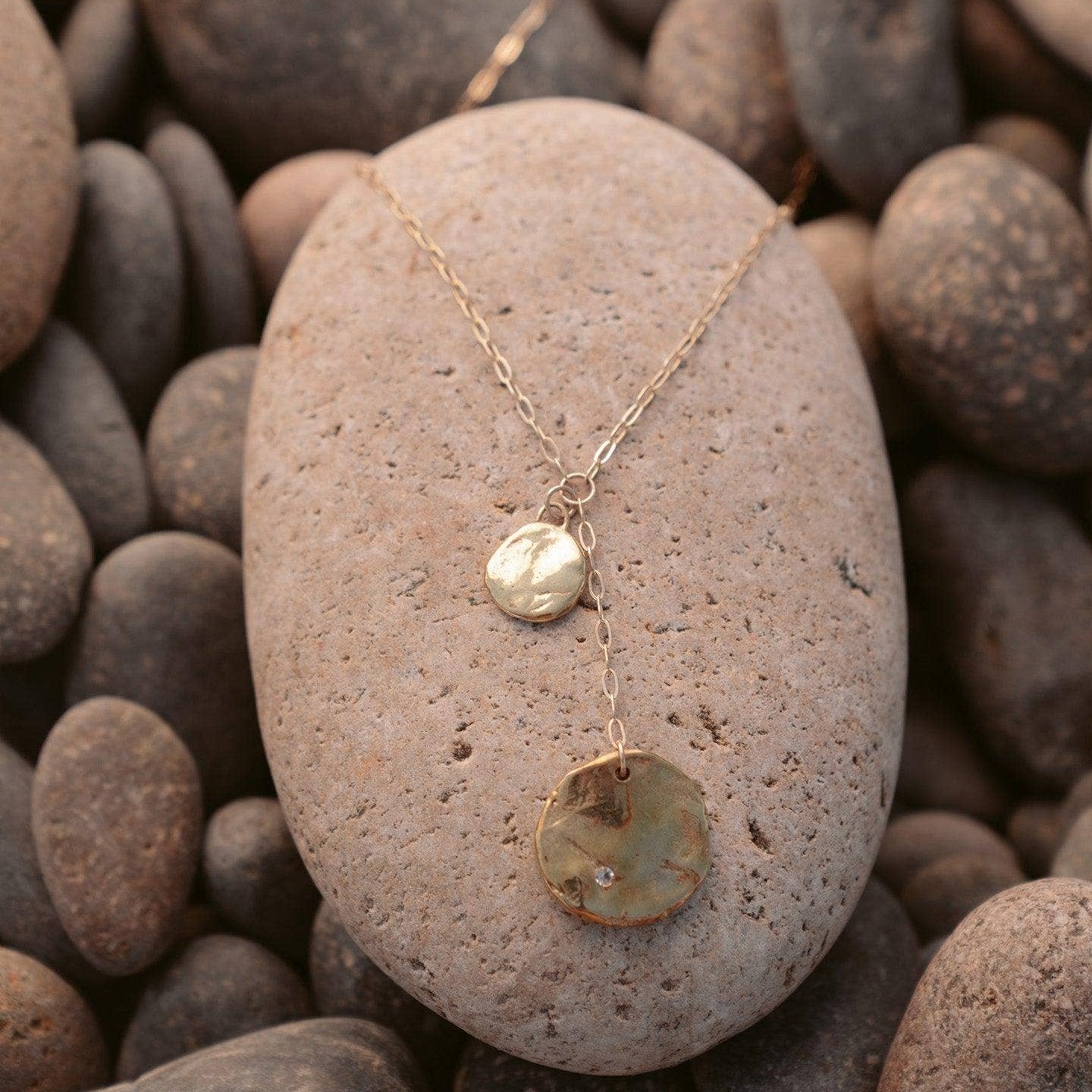 necklace pictured atop a beach stone