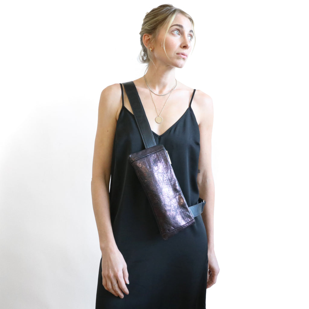 Front view of model wearing district sling in mica amethyst and black crossbody. 