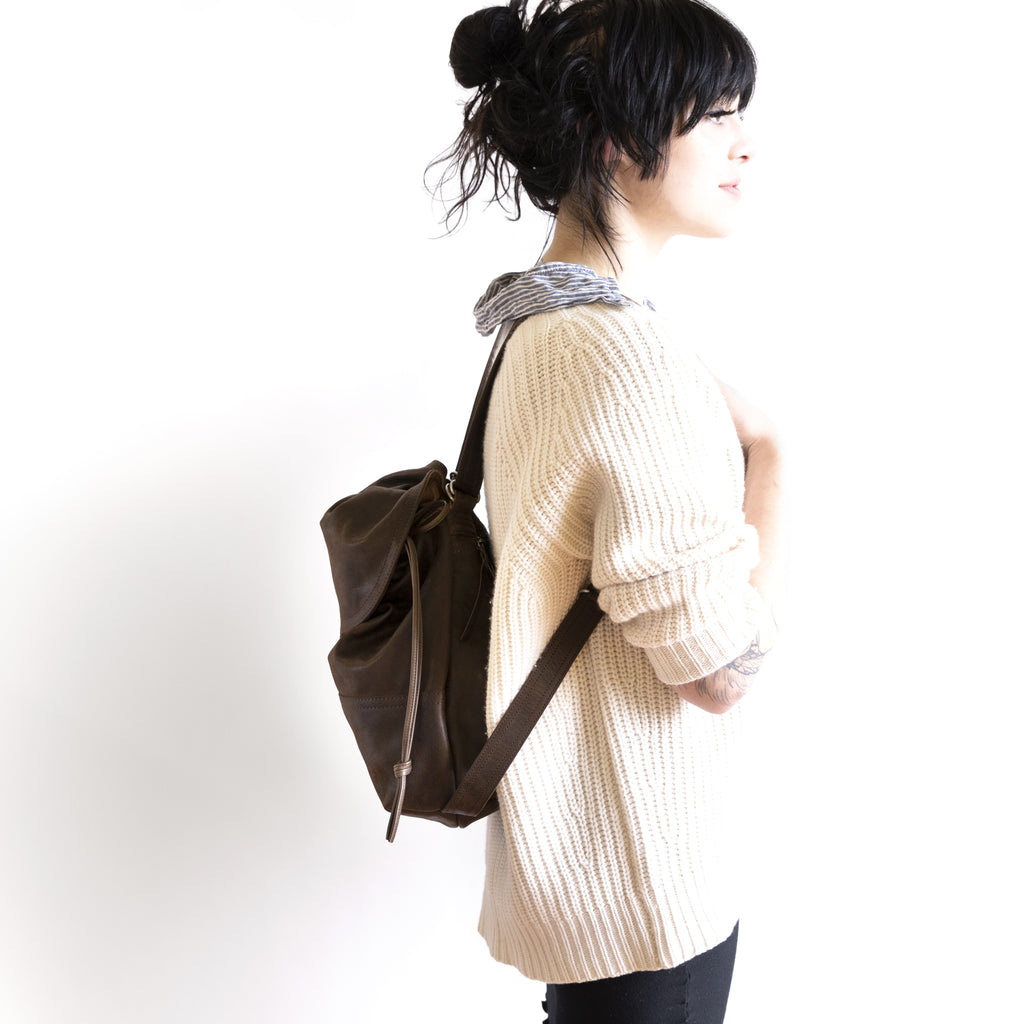 Side view of model wearing 1904 medium as a backpack. 