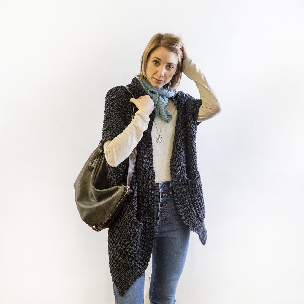 Front view of a model wearing a small duffel on shoulder. 