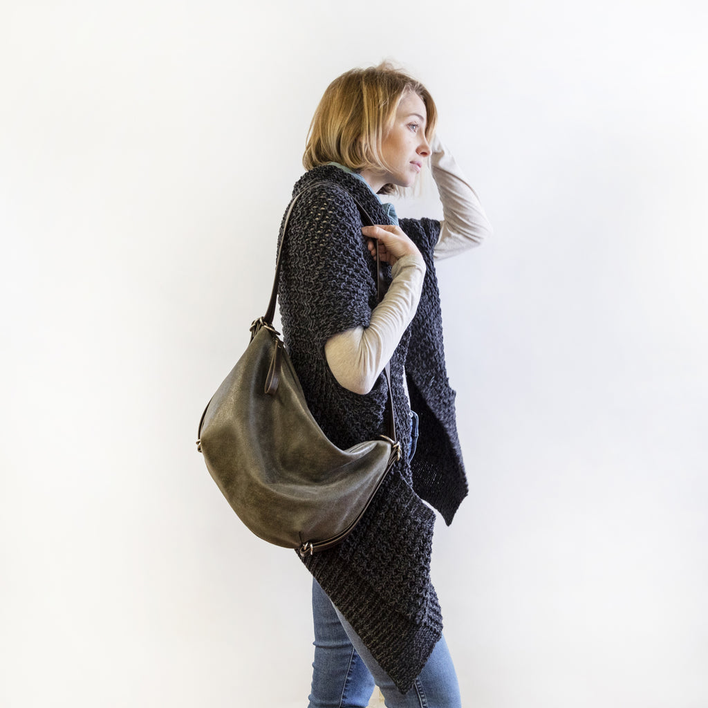 Side view of a model wearing a small duffel on shoulder. 